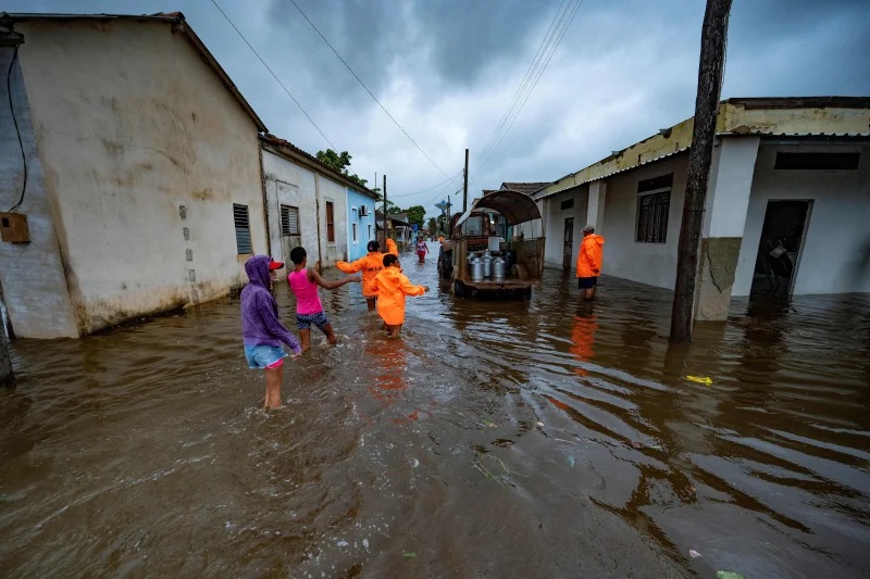 People walk through a flooded street in Batabano