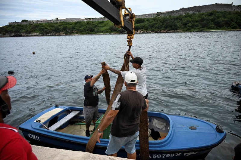 People pull small boats out of Havana Bay in Havana